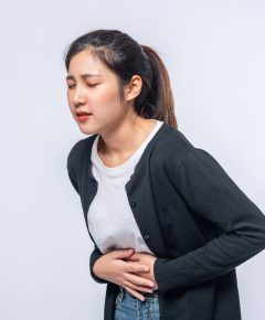 woman-standing-with-stomach-ache-presses-her-hand-her-stomach